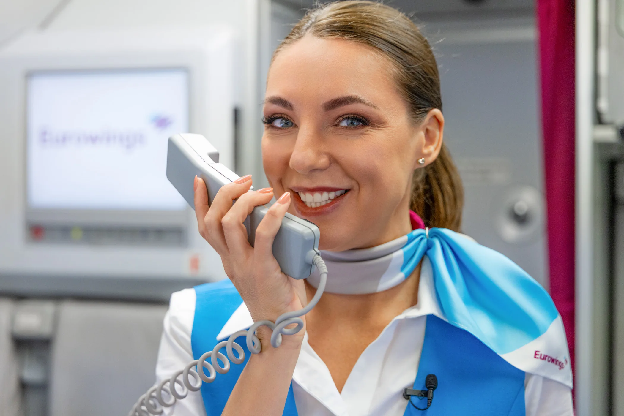 Erklärfilm-Produktion: Flugbegleiterin in Eurowings-Uniform mit Kabinentelefon während der Filmszene an Bord