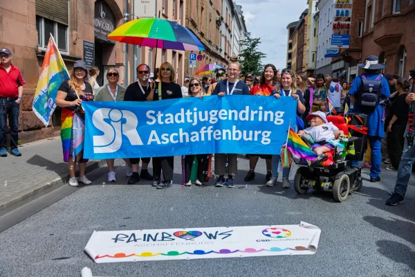 Eventfotograf beim CSD: bunte Schilder und Regenbogenfahnen im Demonstrationszug