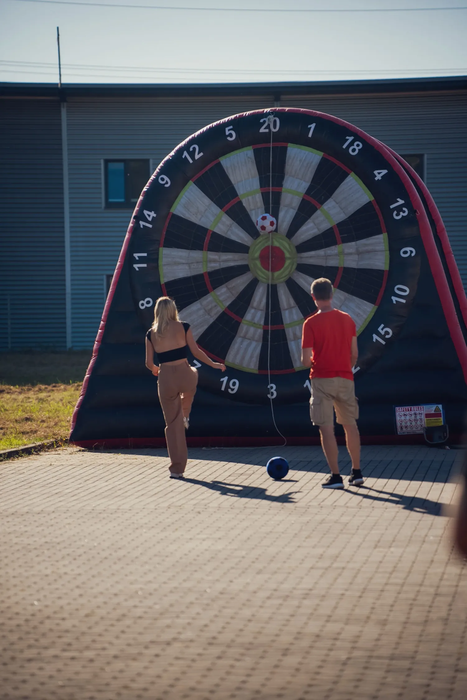 Eventfotografie beim Sommerfest: zwei Gäste beim Torwand-Spiel auf dem Firmengelände