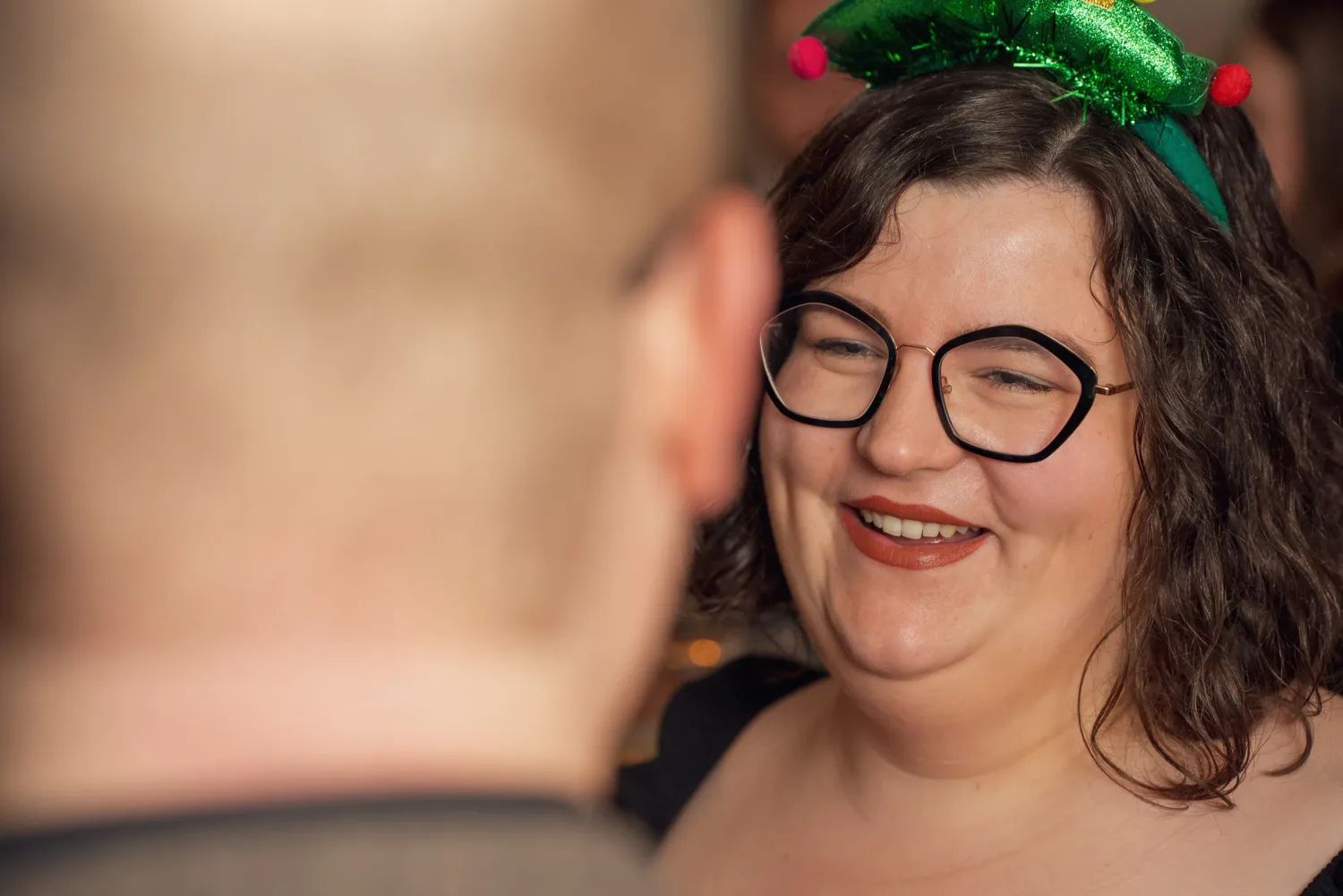 Eventfotograf Aschaffenburg: Gästin mit weihnachtlichem Haarreif lacht während der Weihnachtsfeier