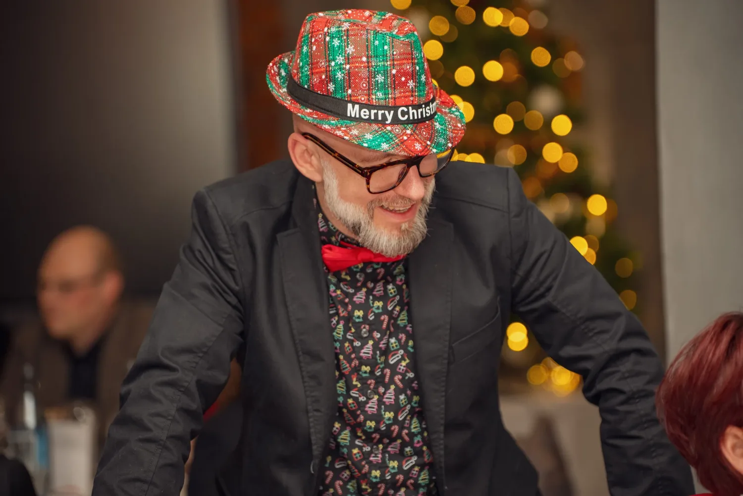 Eventfotografie Firmenfeier Aschaffenburg: Gast mit weihnachtlichem Hut vor dem geschmückten Weihnachtsbaum