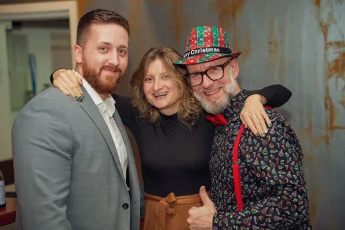 Eventfotografie Weihnachtsfeier: drei Gäste posieren eng zusammen mit Daumen hoch