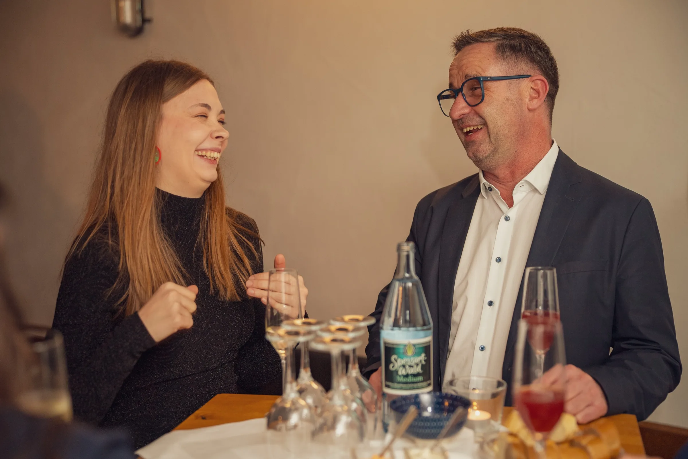 Eventfotografie bei der Weihnachtsfeier: lachendes Paar am Tisch mit Spessart-Mineralwasser