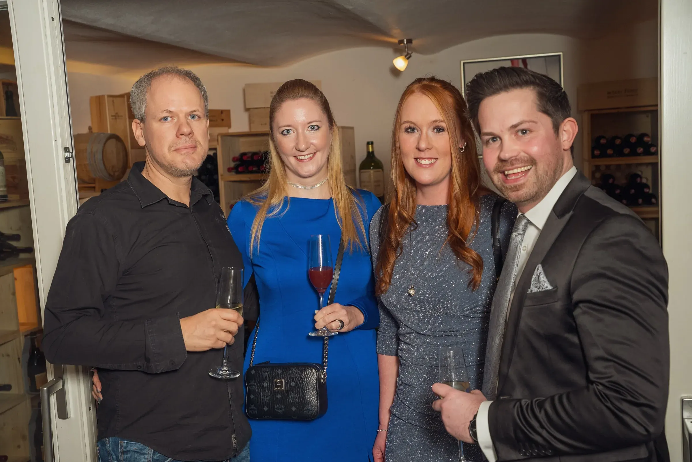 Eventfotograf bei der Weihnachtsfeier: vierköpfige Gästerunde posiert im Weinkeller