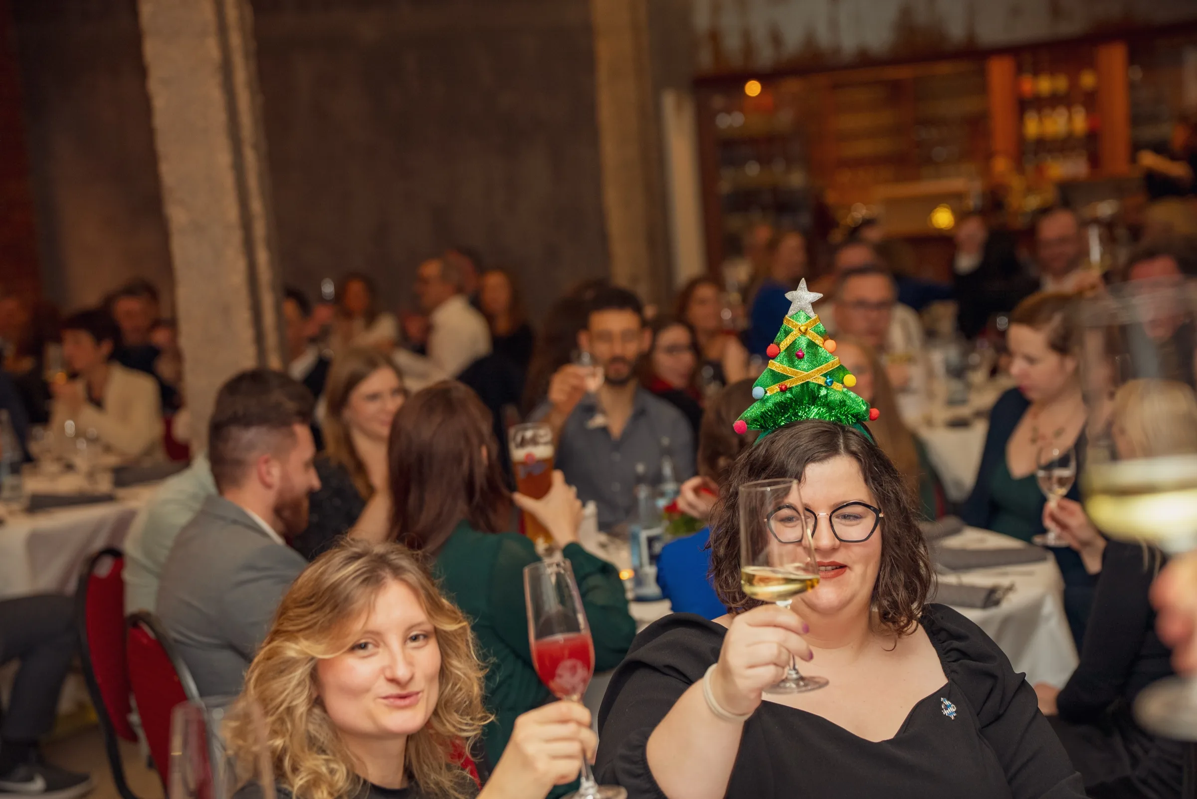 Eventfotografie Weihnachtsfeier Aschaffenburg: voller Saal beim Anstoßen mit Sekt und Wein