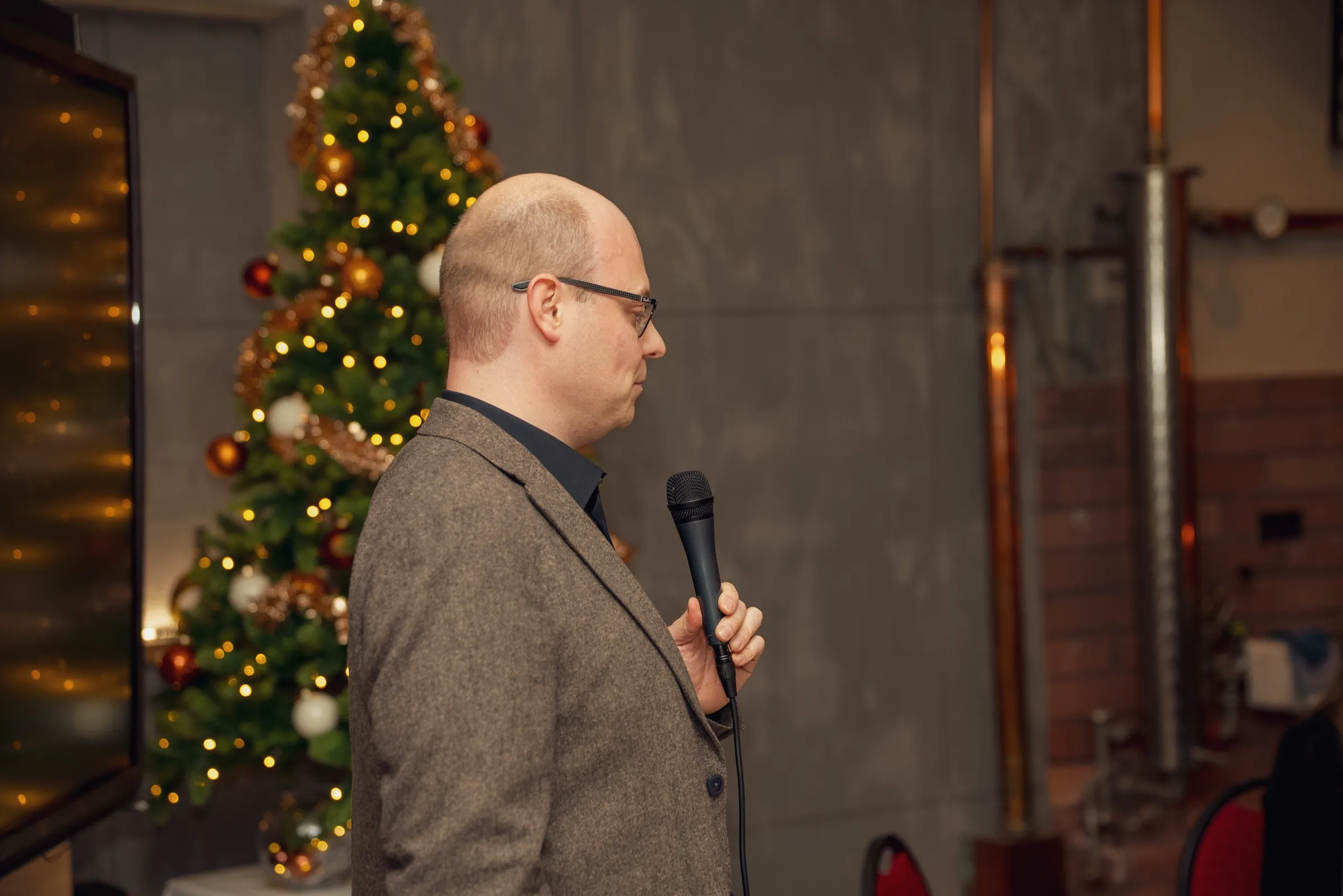 Eventfotograf bei der Weihnachtsfeier: Redner mit Mikrofon vor dem Weihnachtsbaum