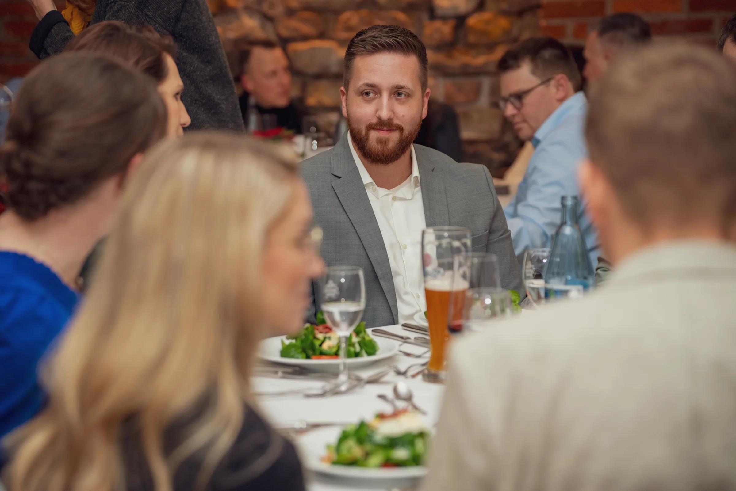 Eventfotografie bei der Firmenweihnachtsfeier: Tischrunde beim Vorspeisengang mit Salat und Bier