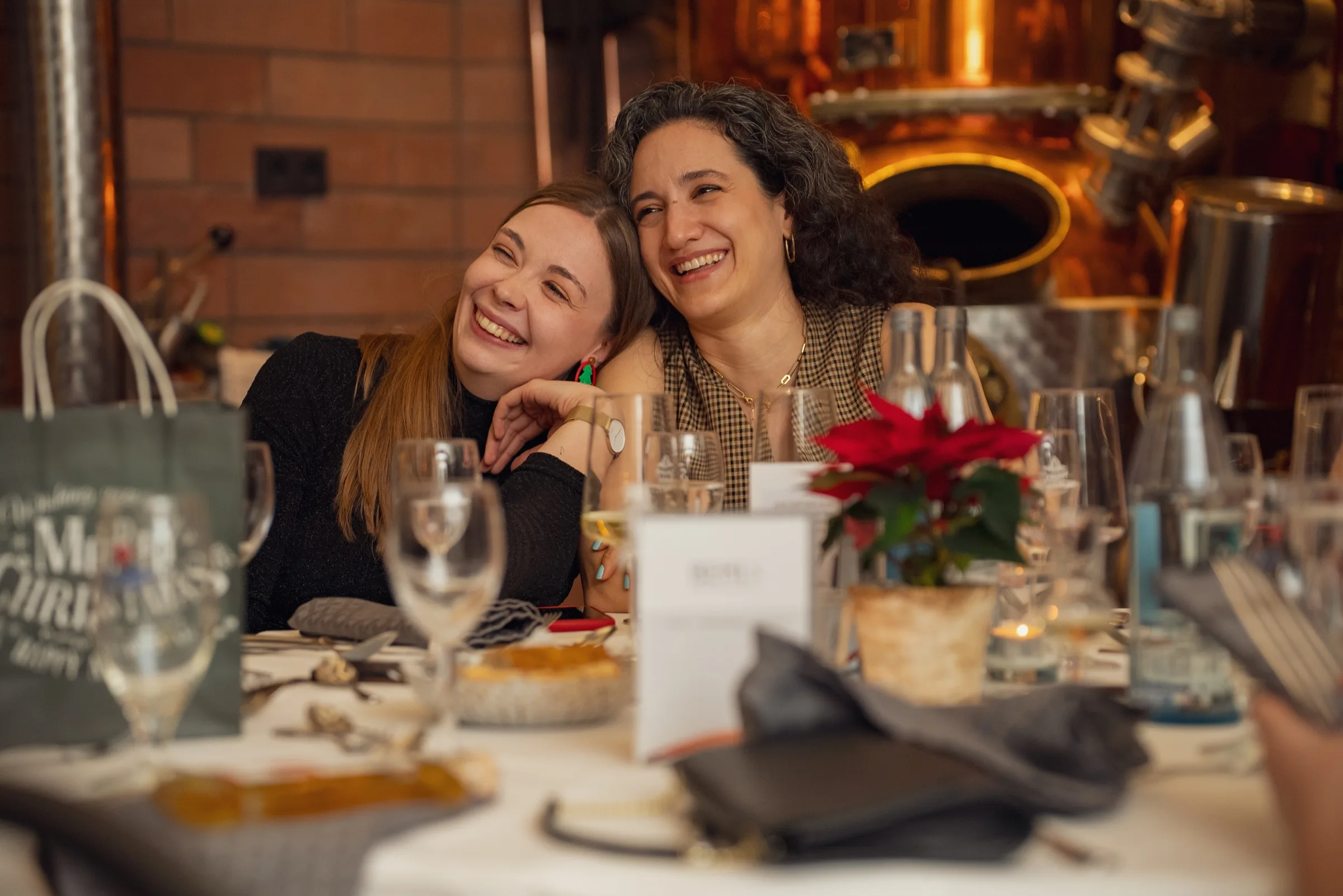 Eventfotograf bei der Weihnachtsfeier: zwei Gäste lachen ausgelassen am festlich gedeckten Tisch