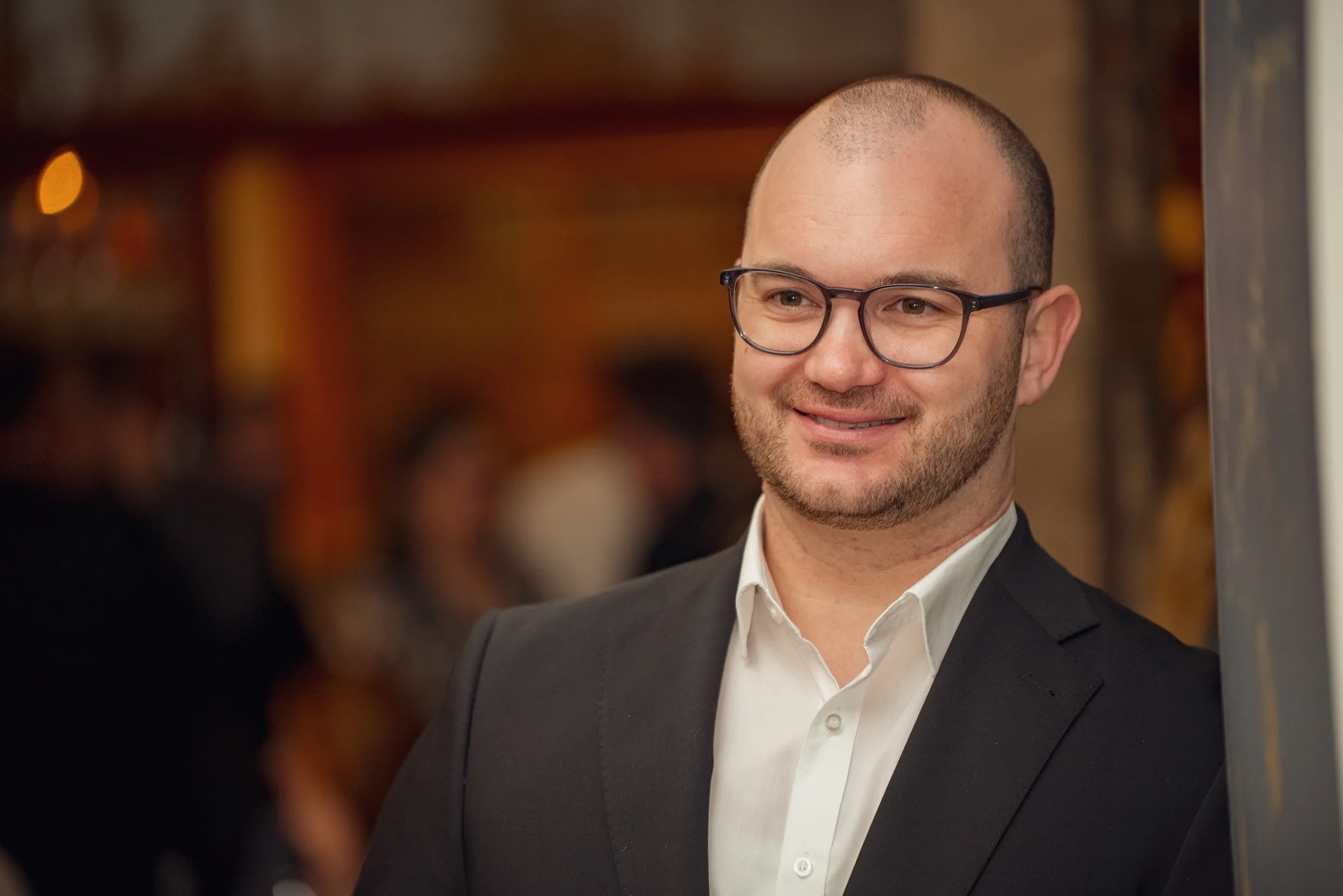 Eventfotografie Firmenfeier Aschaffenburg: Porträt eines lächelnden Gastes im Anzug
