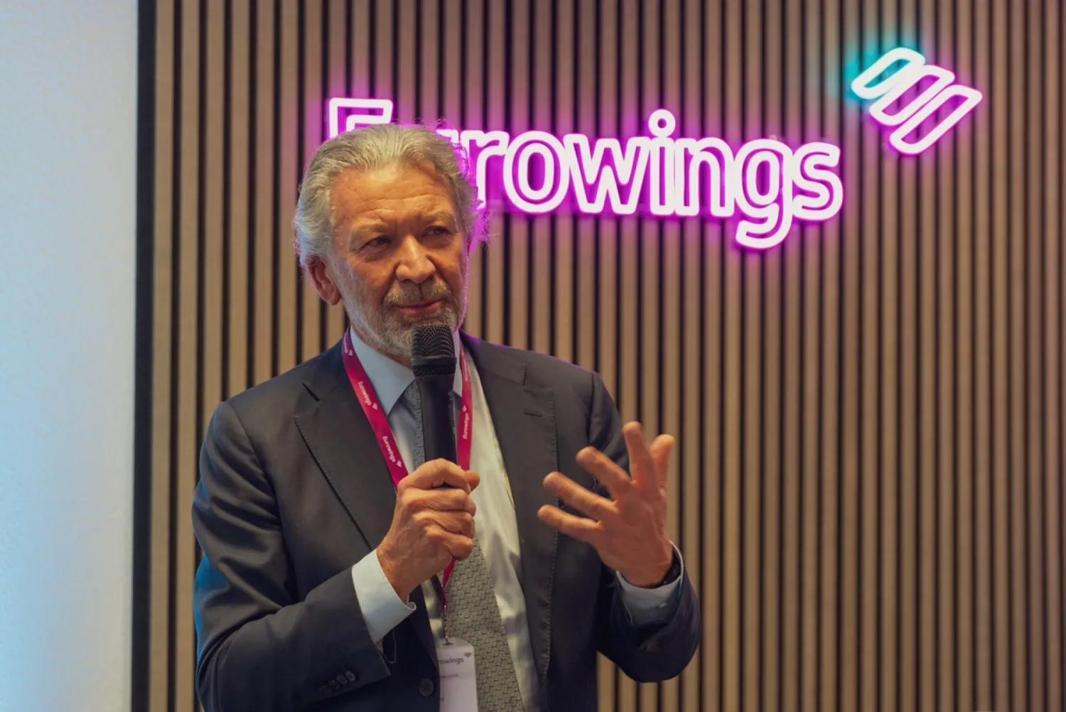 Videoproduktion für Eurowings Aschaffenburg: Redner mit Mikrofon vor dem leuchtenden Eurowings-Schriftzug