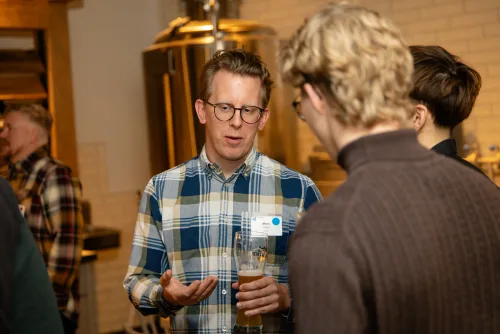Eventfotografie Netzwerkabend: Gäste mit Namensschild beim Empfang der After Work Lounge